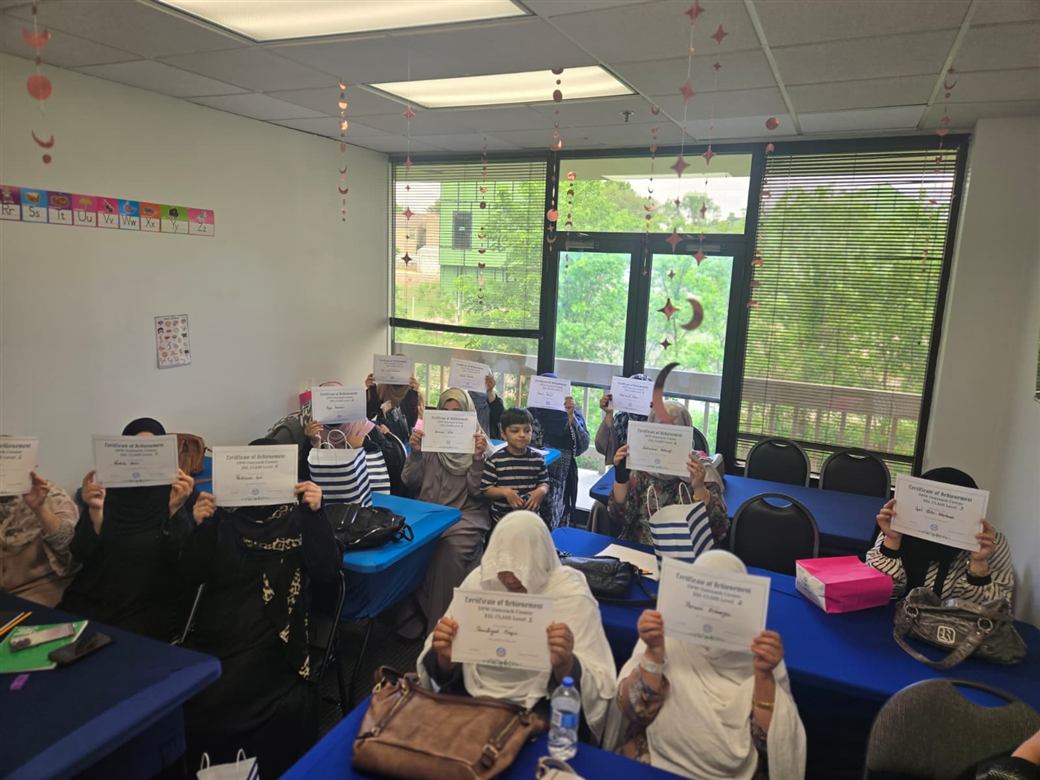 ESL graduates holding up their certificates of achievement
