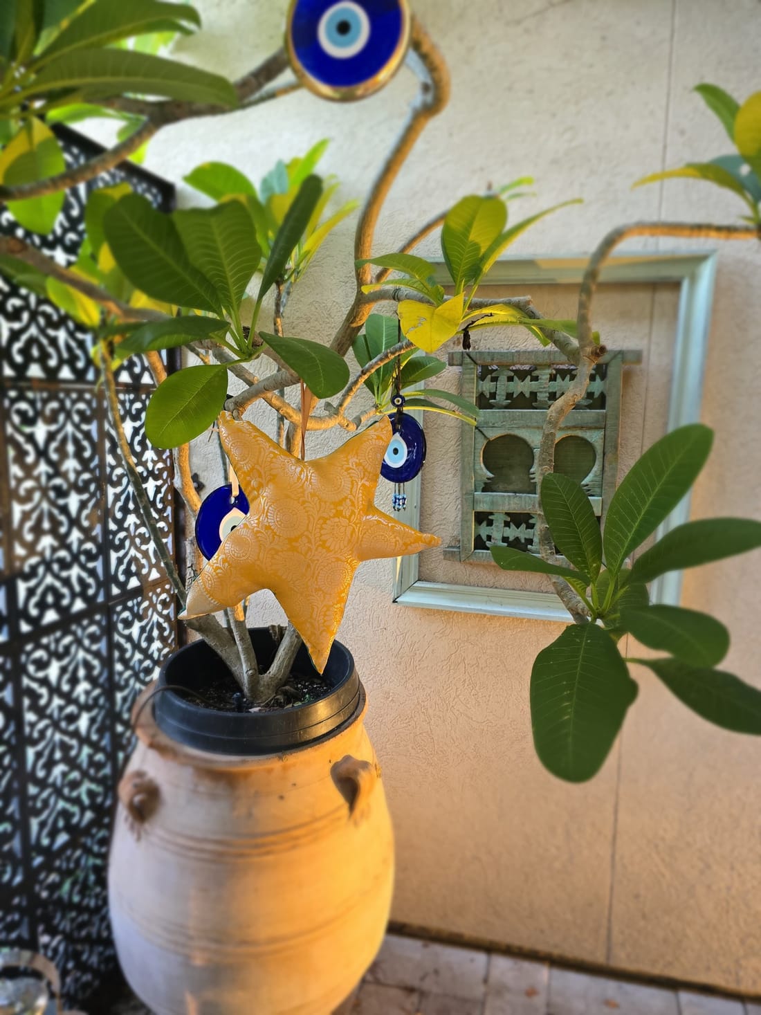 A hand-sewn star ornament in gold brocade, hanging from a plant