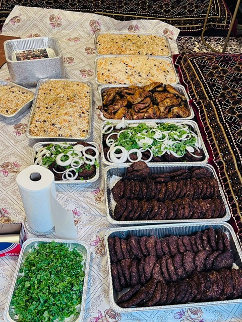 Hope Kitchen catering spread &mdash; trays of rice, grilled chicken, kebabs, salad and herbs